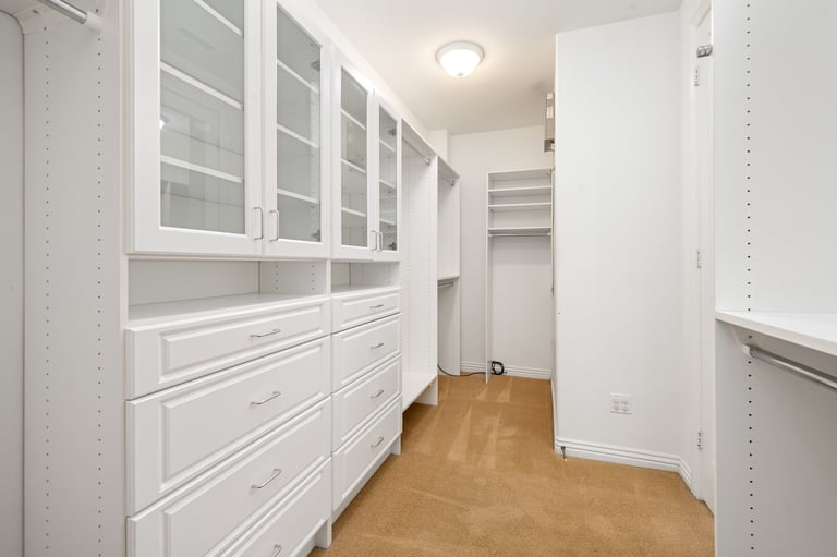 White built-in cabinets in narrow walk-in closet