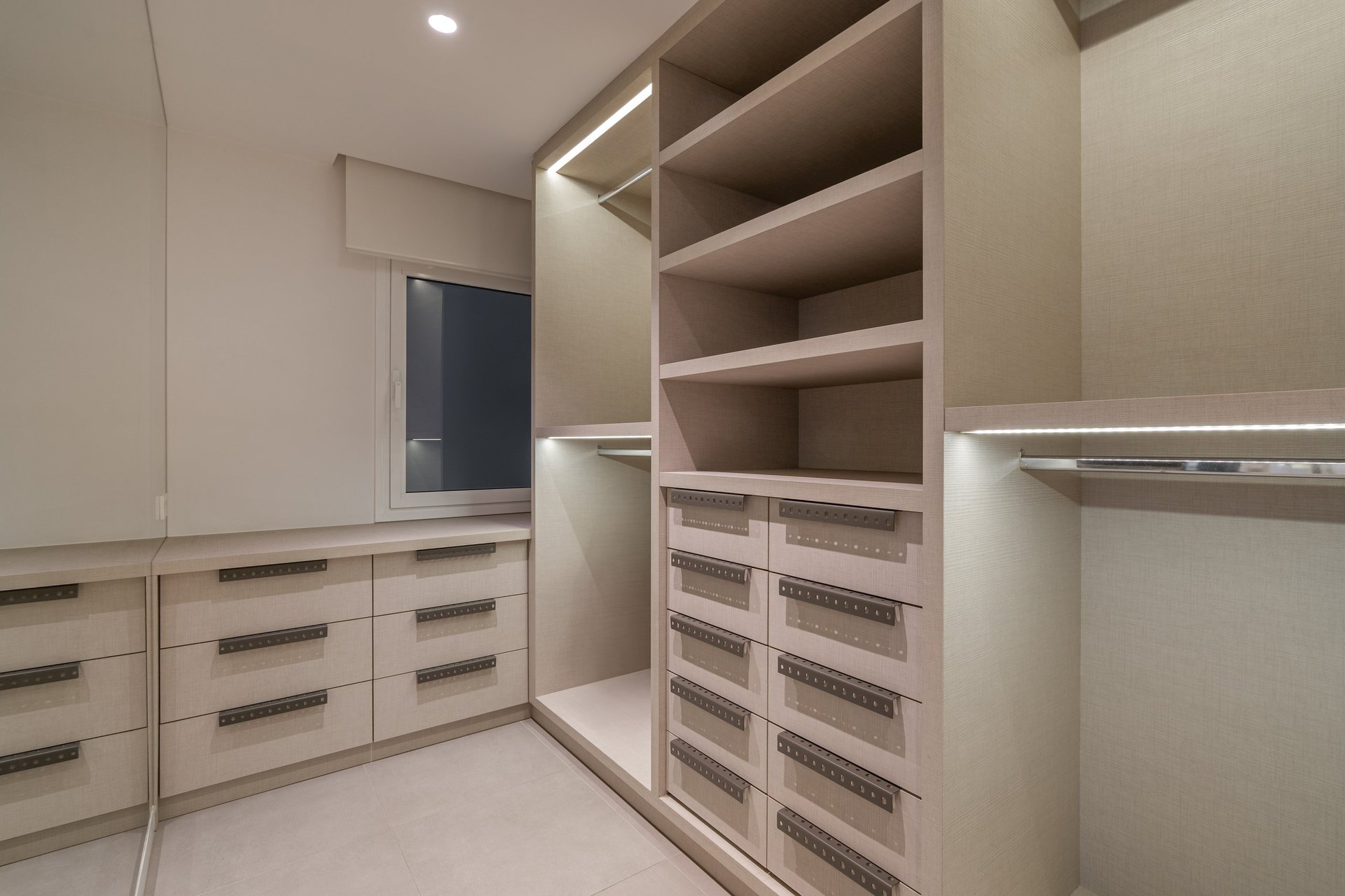 Modern spacious walk-in closet with built-in shelves and drawers